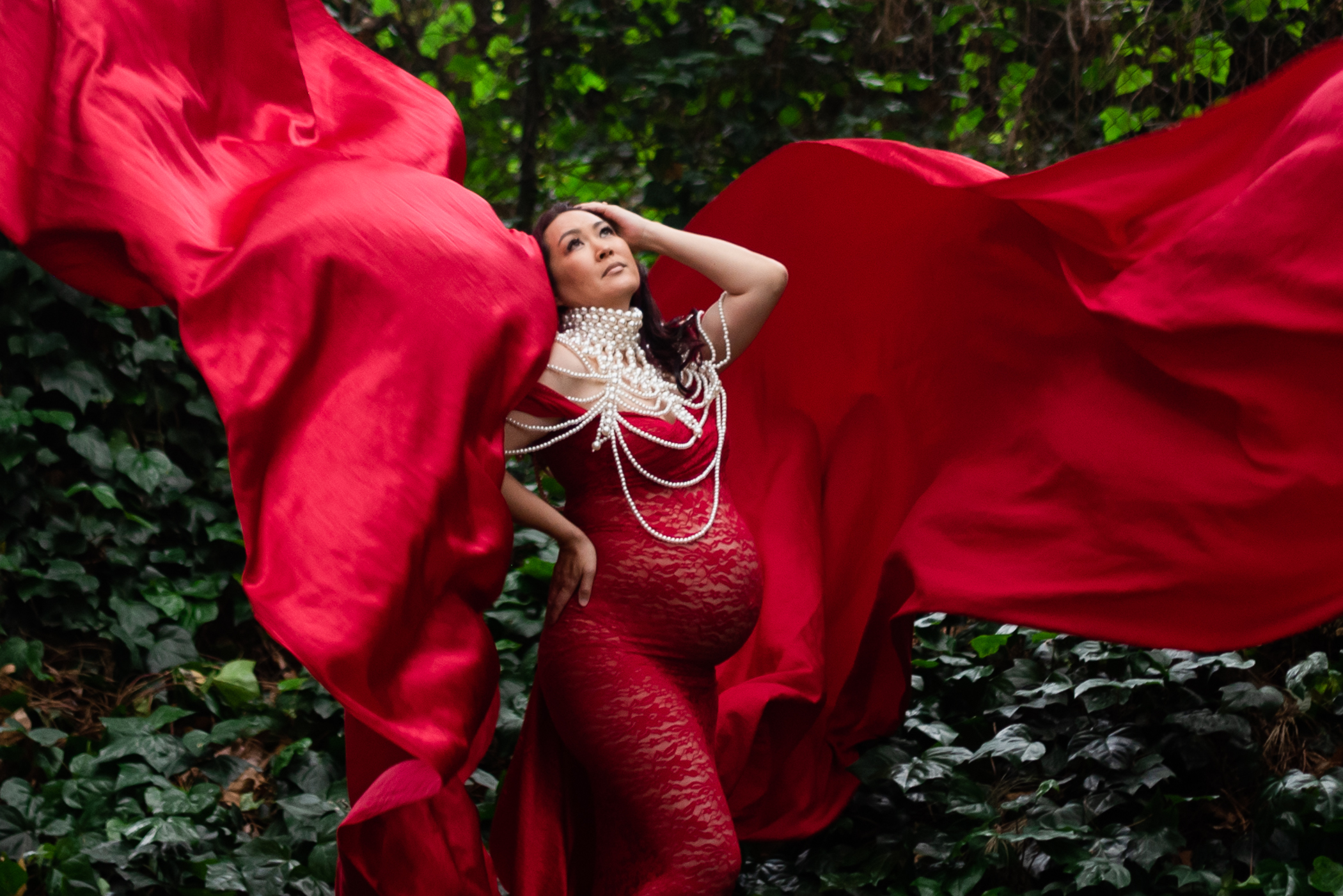 Maternity in a red tossing dress with pearls