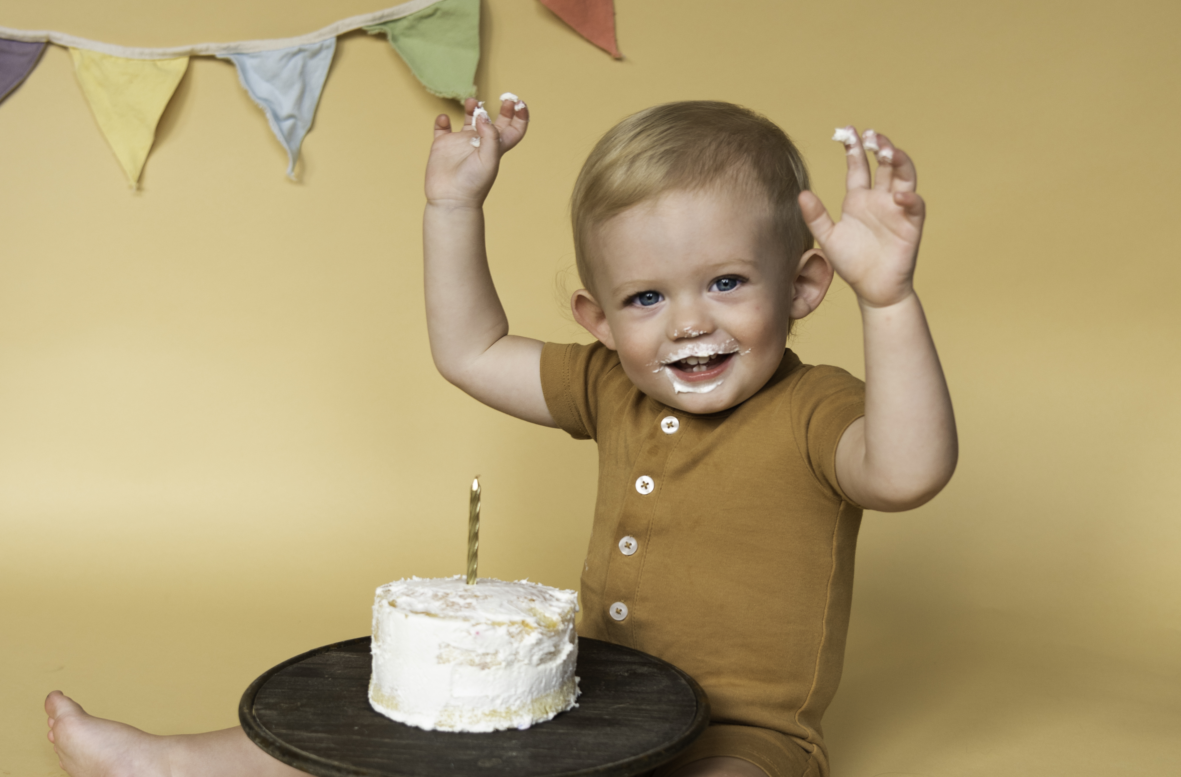 1 year old boy with his cake on brown backdrop