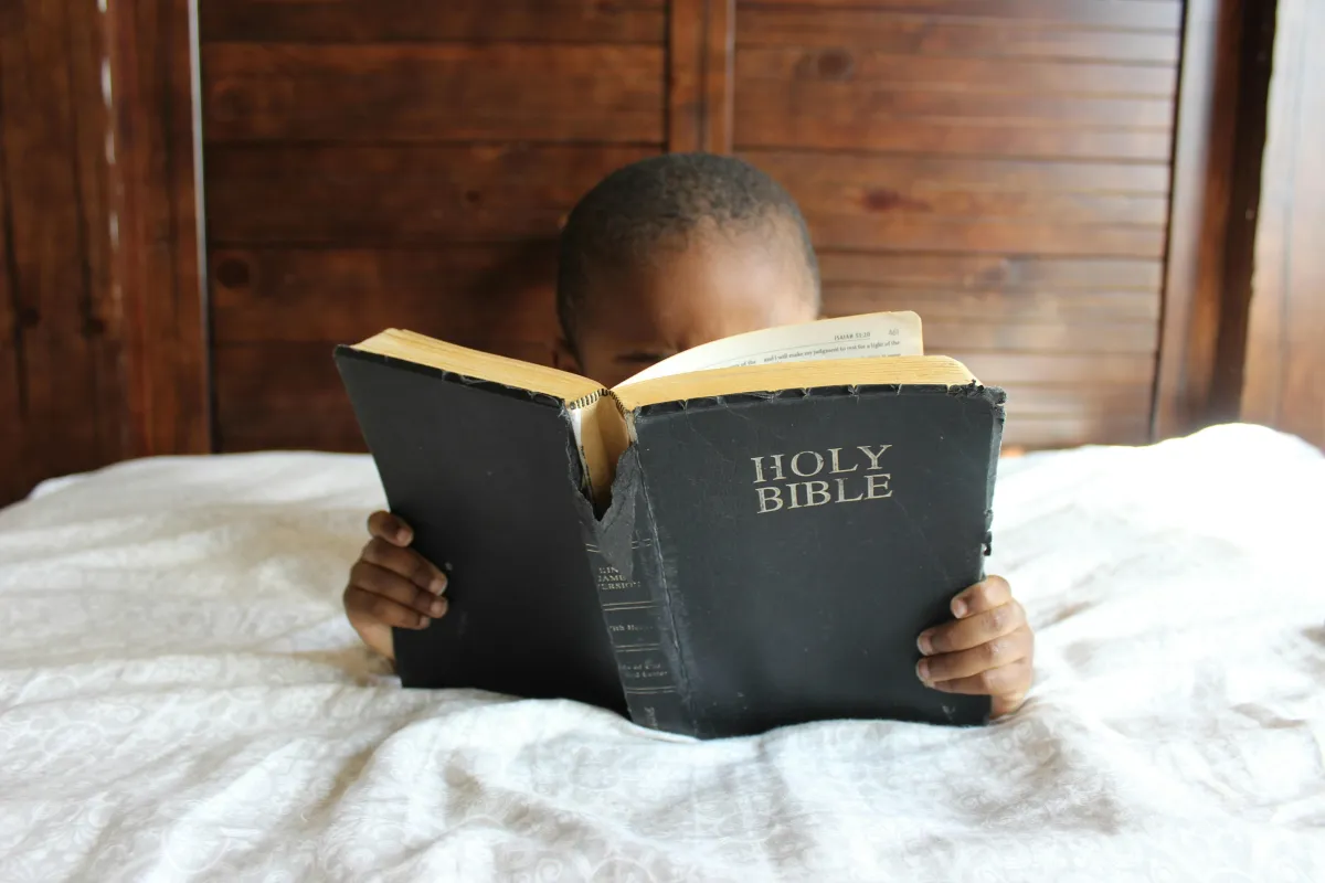 toddler in the bed reading the Bible