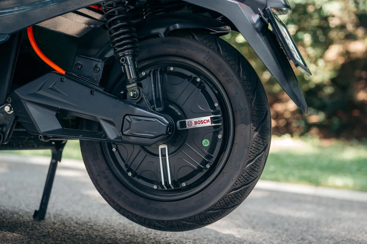 Zadnje kolo električnega skuterja VeloVoltage Retro z vgrajenim BOSCH motorjem, vzmetenjem in elegantnim temnosivim ohišjem pod rjavim sedežem.