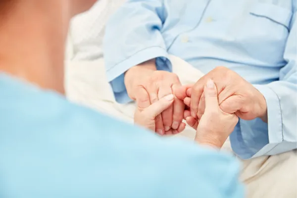 Caregiver Holds the Hands of a Sick Senior Citizen