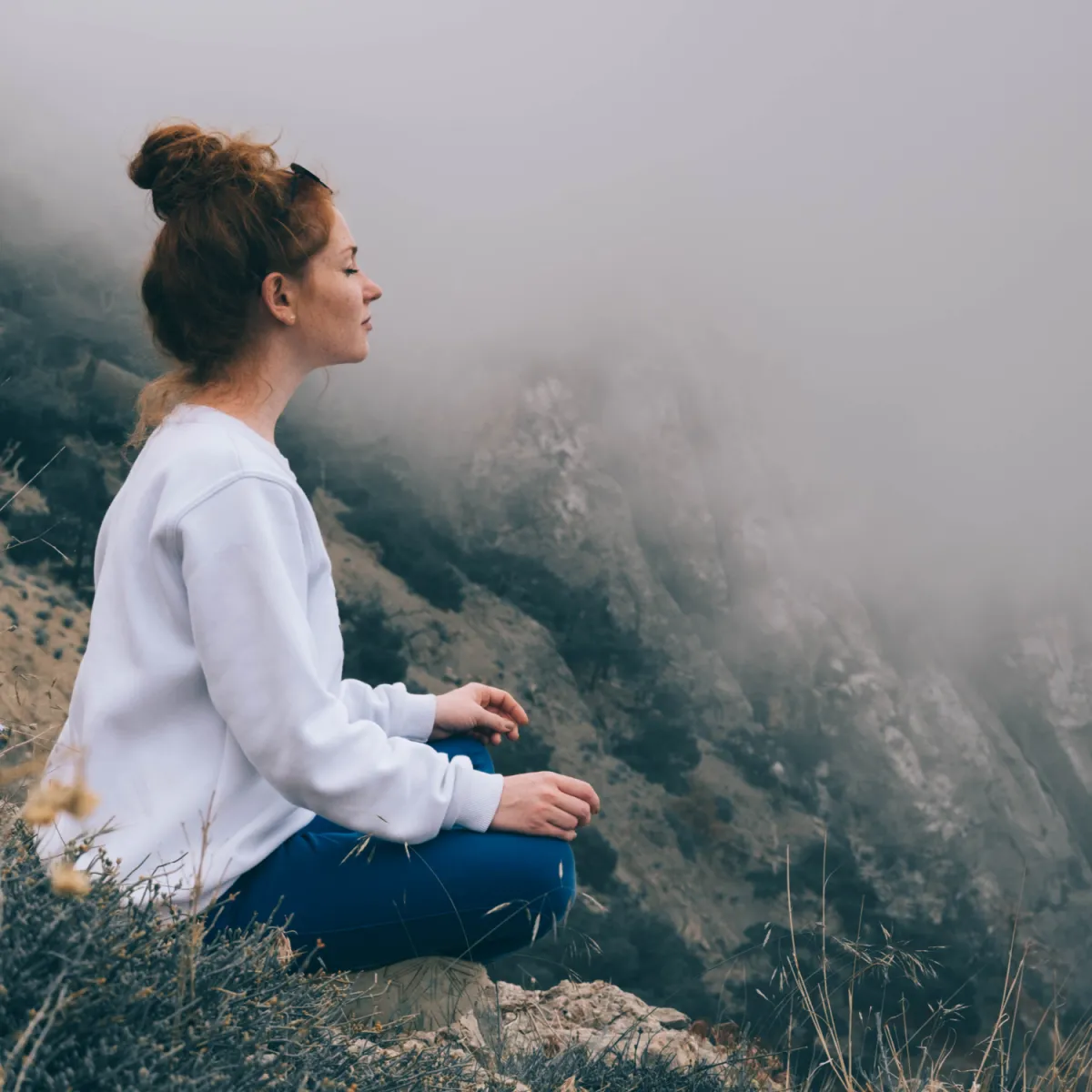 woman meditating in fog on a hillside