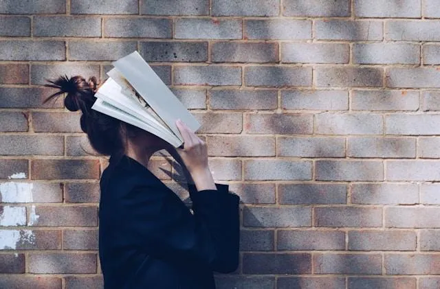 woman with book over face