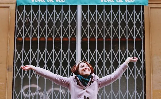 woman happy with arms up by building