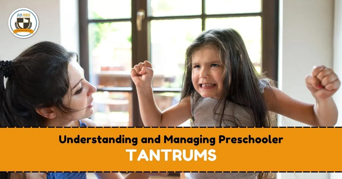 A young girl with long hair appears upset, raising her fists and grimacing in frustration, while an adult woman looks at her calmly, offering support. Text overlay reads ‘Understanding and Managing Preschooler Tantrums’ and the Jus Kids International School logo appears in the top left corner.