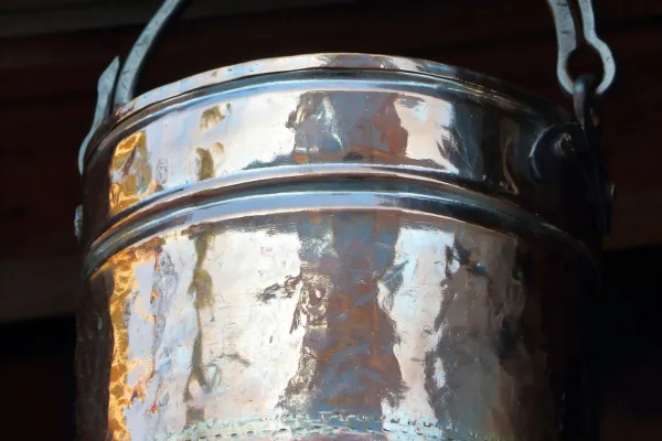 Old weathered metal bucket with a hole in the bottom, symbolizing emotional wounds, generational trauma, and the sacred work of healing