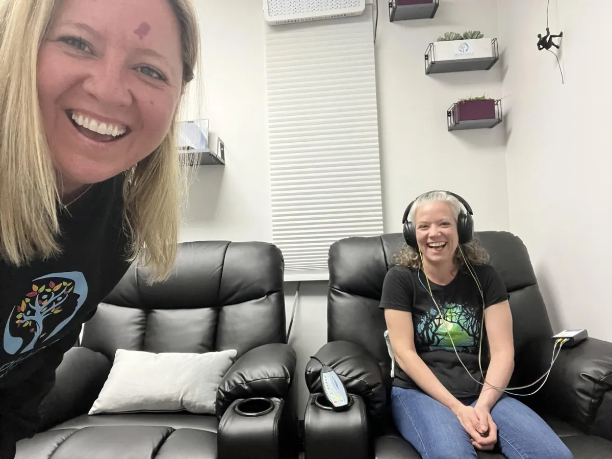 Person relaxing in a cozy chair with headphones, symbolizing calm and clarity through neurofeedback brain training at NeurPhoria.