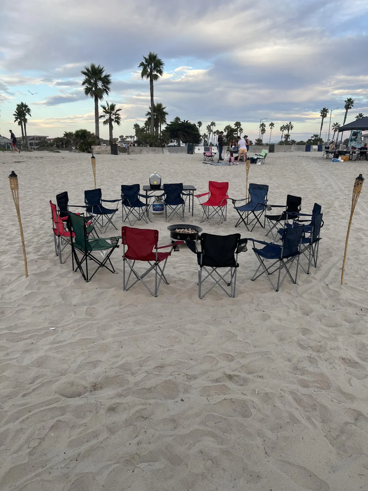 Sunset beach bonfire with ocean view and people soon to be relaxing around the fire.
