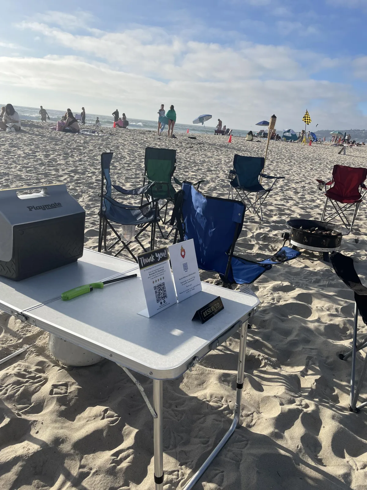 Mission Beach bonfire setup with propane firepit, tiki torches, and seating