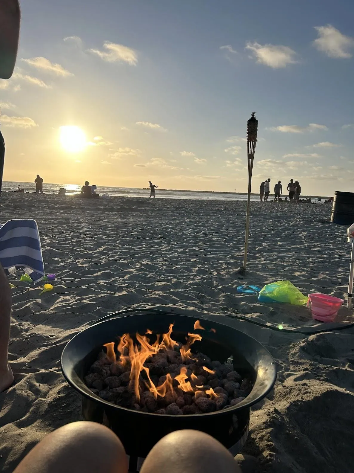 A San Diego sunset with bonfire rental setup, firepit, and tiki torches.