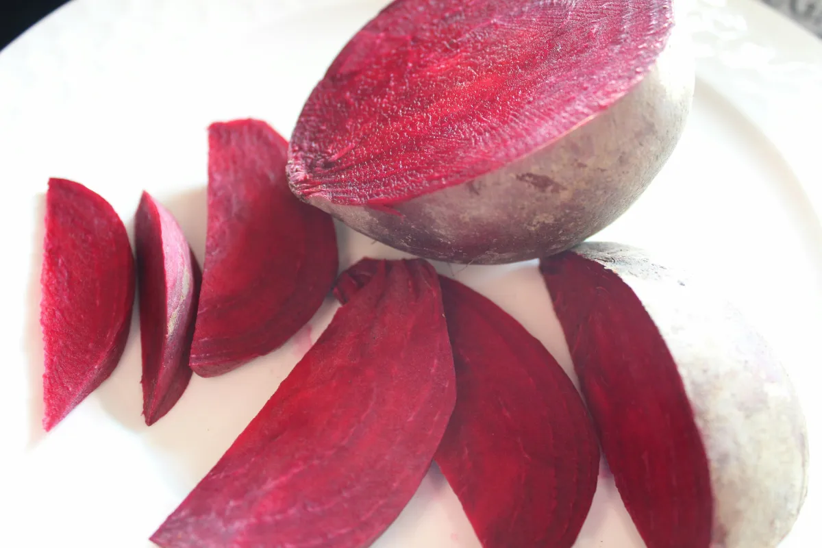 A beet root is sliced up on a white plate