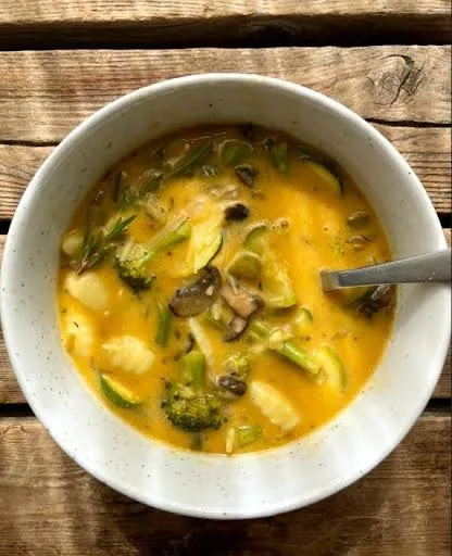 A bowl of the soup sits on a wooden table