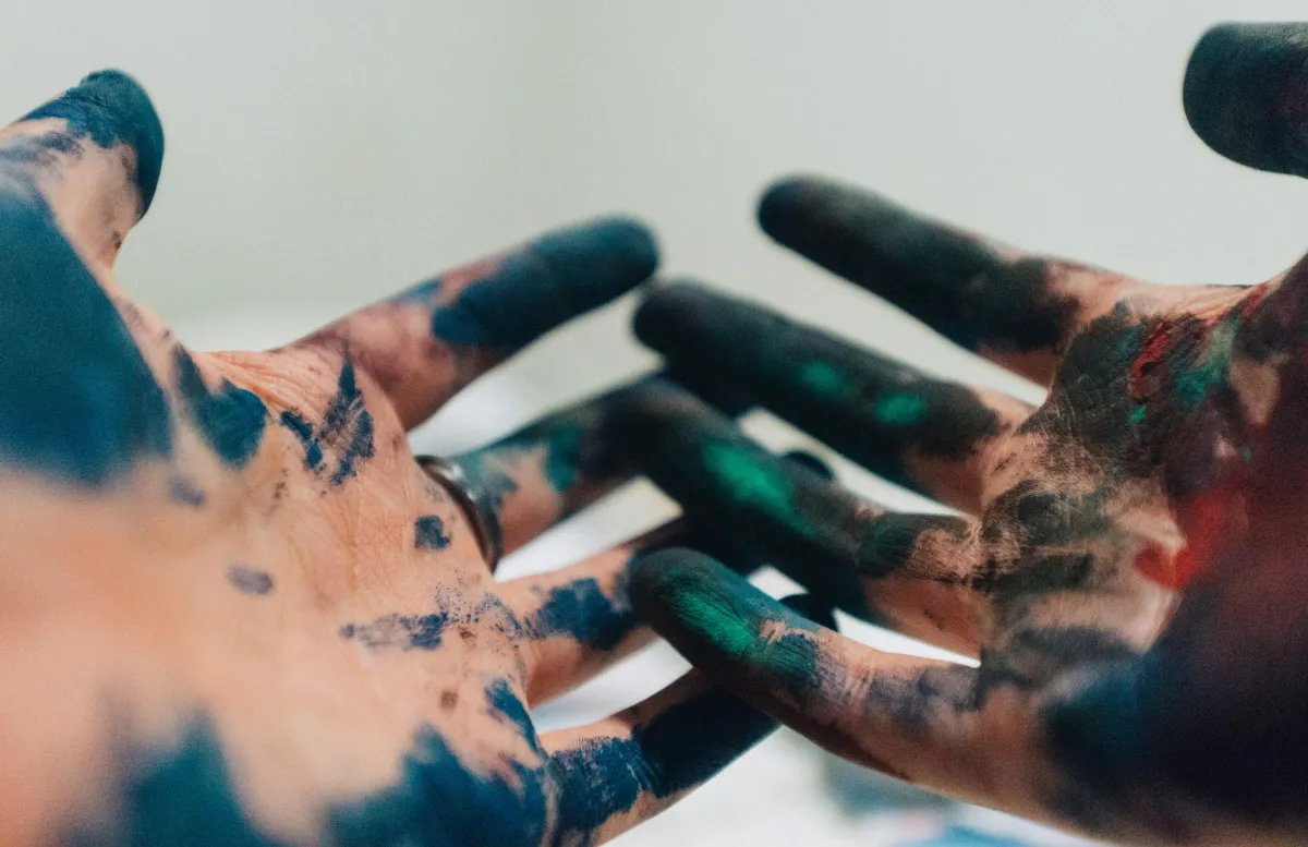Image of two hands mostly covered in blue-green paint