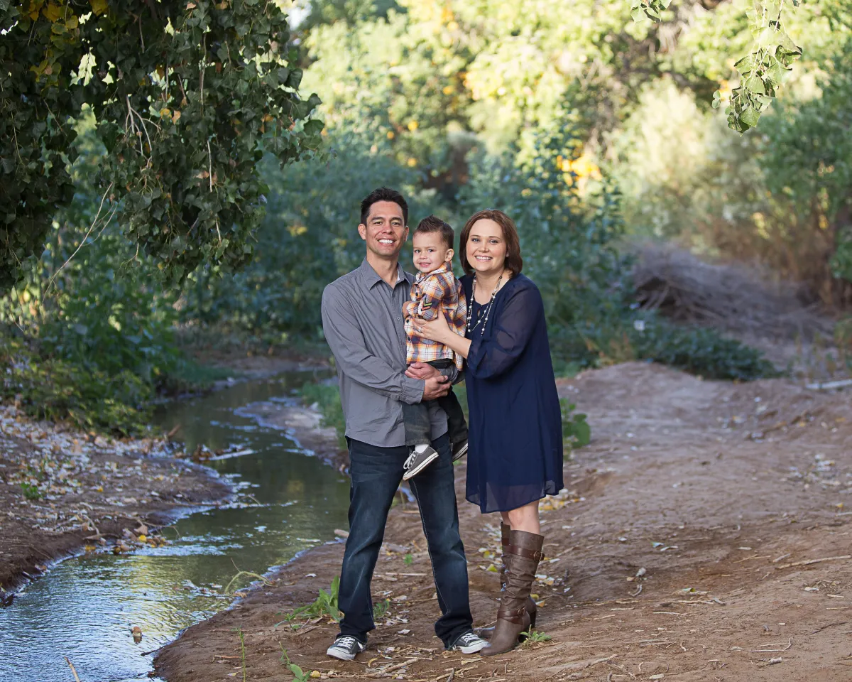 Family portrait at the Riparian Preserve in Gilbert AZ, parents holding their baby near the water during a fall photo session.