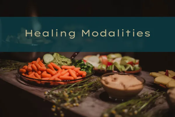 An assortment of fresh vegetables and dips displayed on a wooden table with the text 'Healing Modalities' overlaid.
