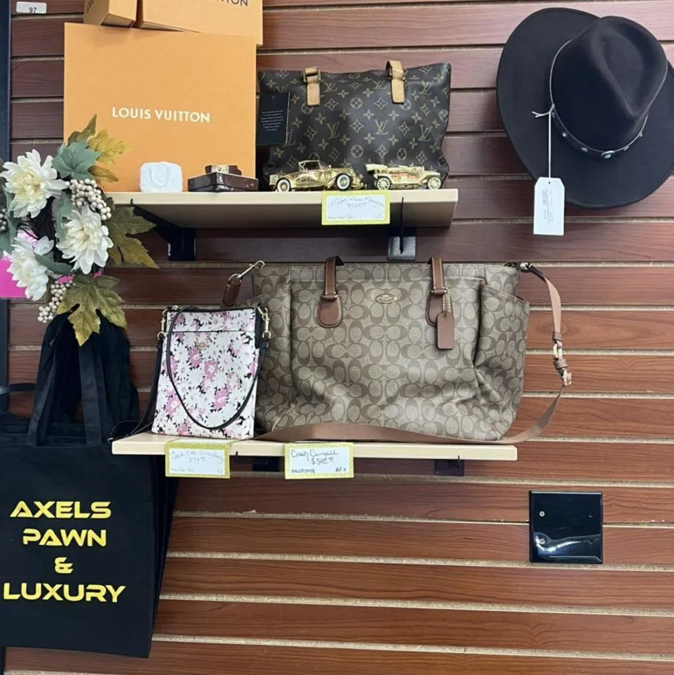 Two staff members at Axel’s Pawn counter displaying an authenticated designer handbag