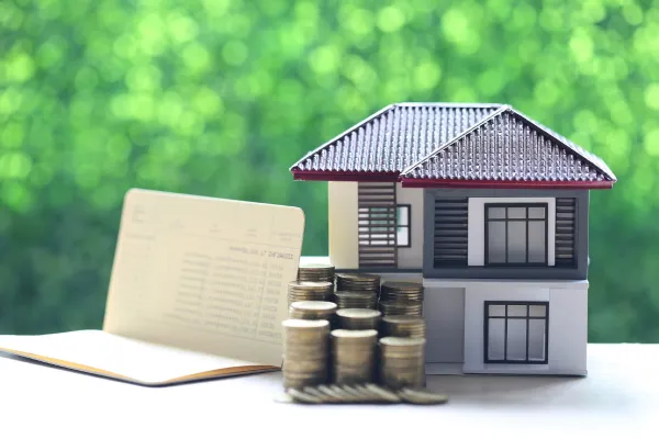 A house model, a notebook, and a stack of coins