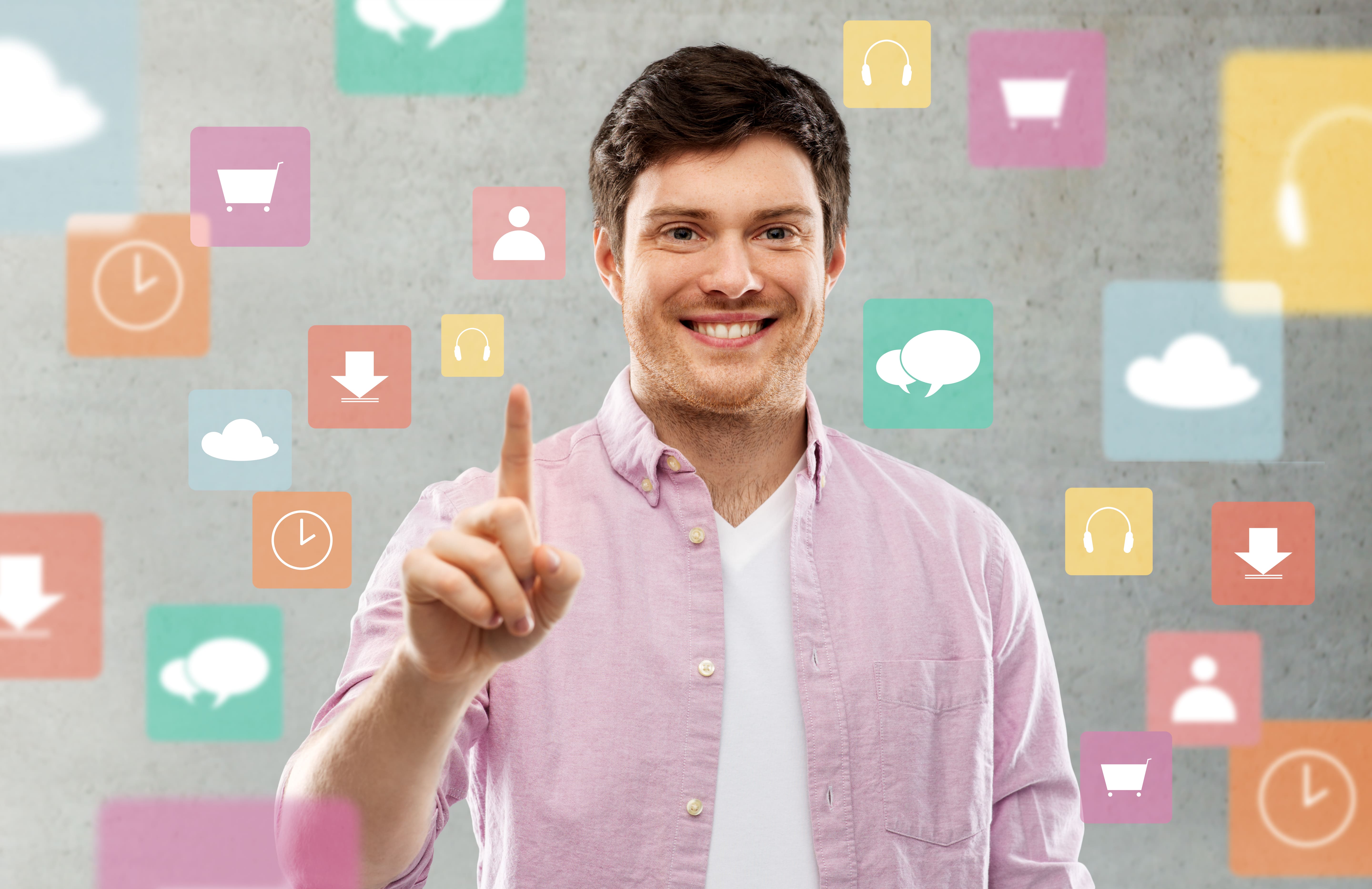 A smiling young man in a pink shirt and white t-shirt points his finger toward the viewer, surrounded by floating, colorful app icons representing e-commerce, cloud storage, downloads, social media, and time.