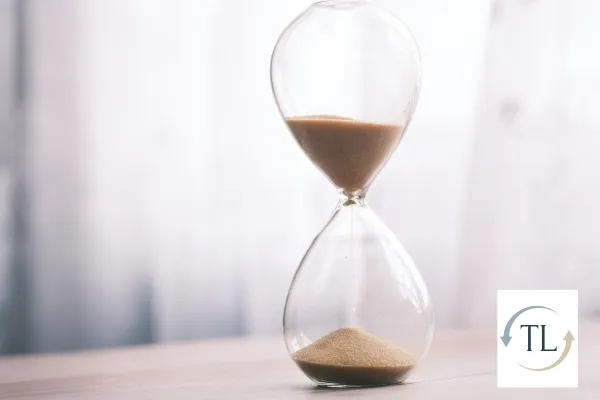 Image of an hour glass with sand about half way between the top and the bottom