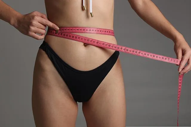 Woman in Black Panties Holding Tape Measure Around Stomach Weight Loss