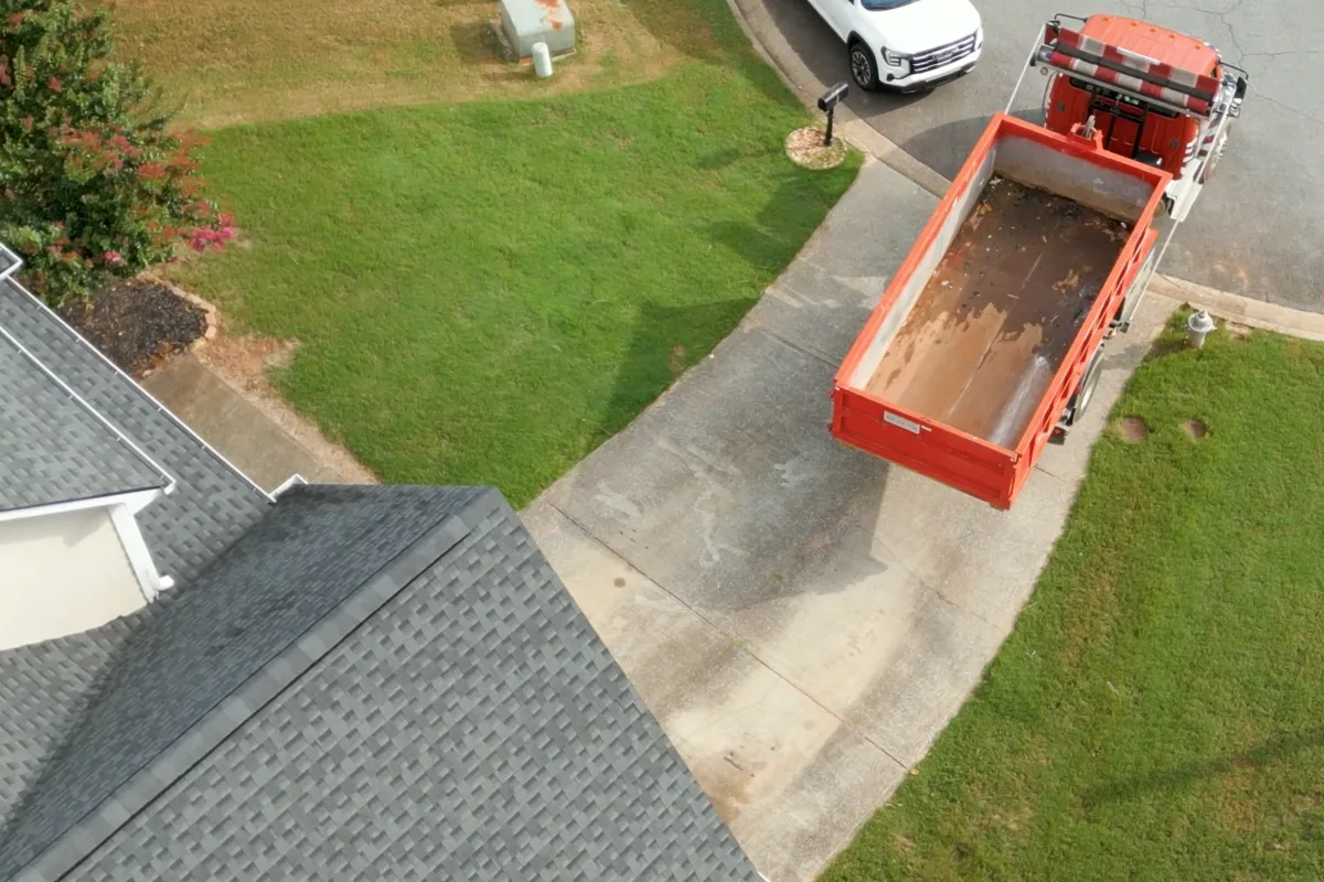 an Elite Disposal Services truck backs up a dumpster to a house.