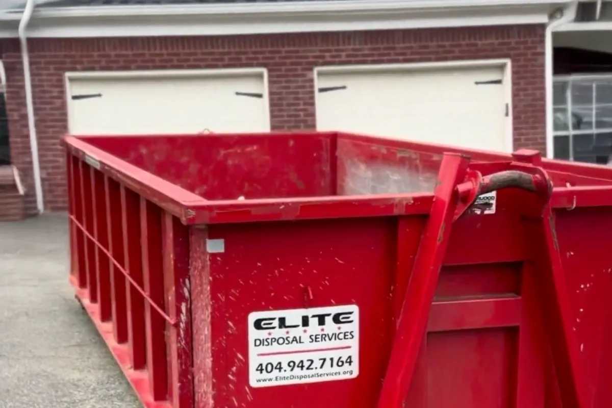 A red Elite Disposal Services sits on a residential driveway.