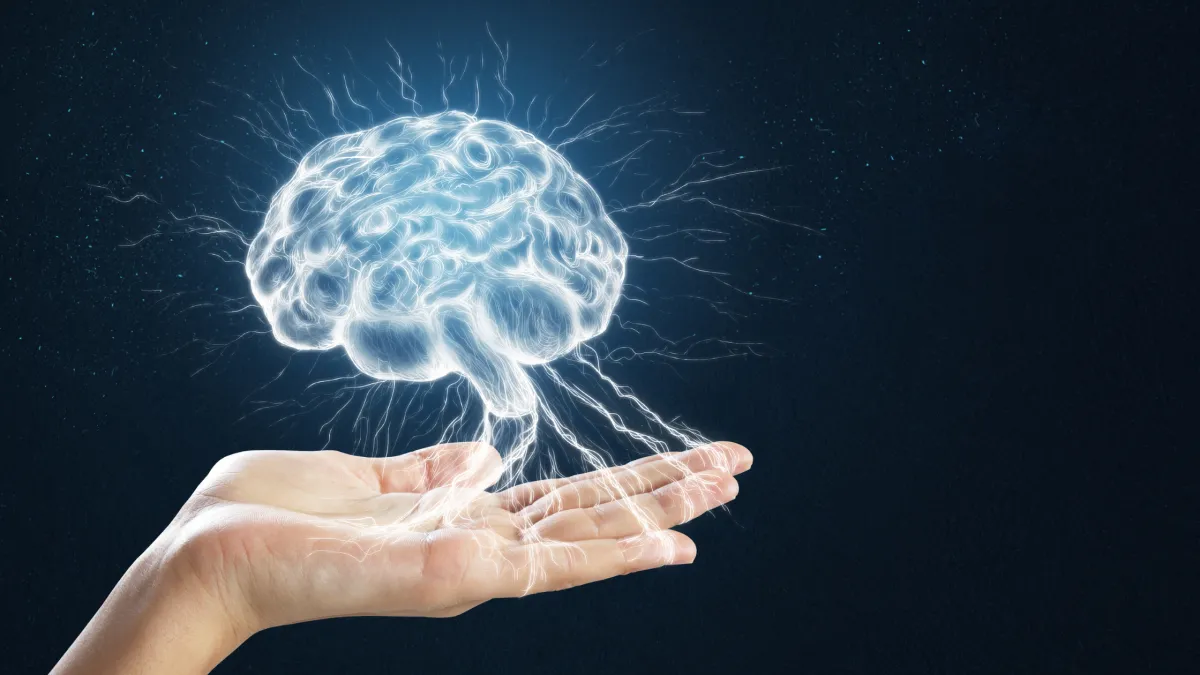 An open hand gently holds a glowing, electric-blue brain surrounded by light energy—symbolizing neuroplasticity, healing, and the power to rewire the mind. This powerful visual supports the blog theme of calming the nervous system and rediscovering clarity in midlife.