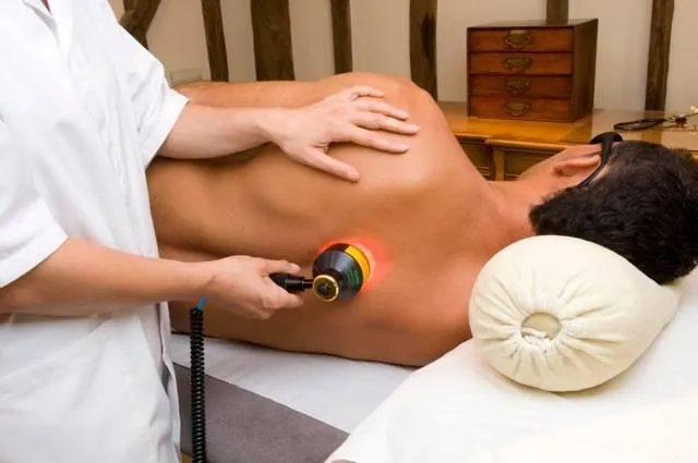 Woman receiving photobiomodulation treatment by a doctor in a therepeutic clinic.
