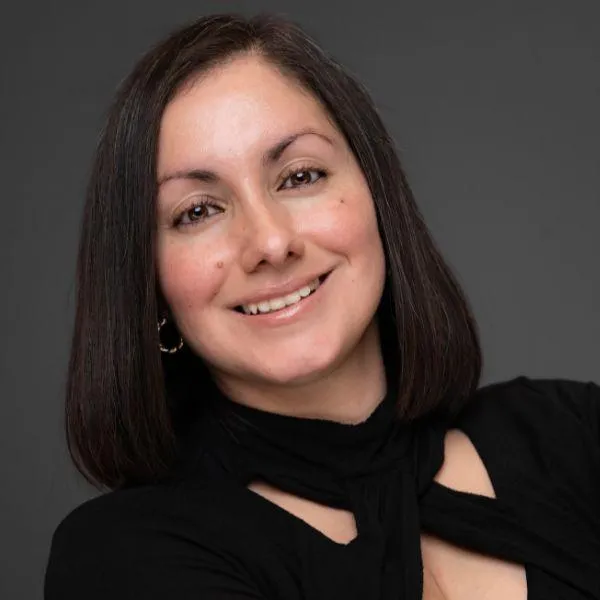 Professional headshot of a smiling Latina doctor in business casual attire, taken for a social profile