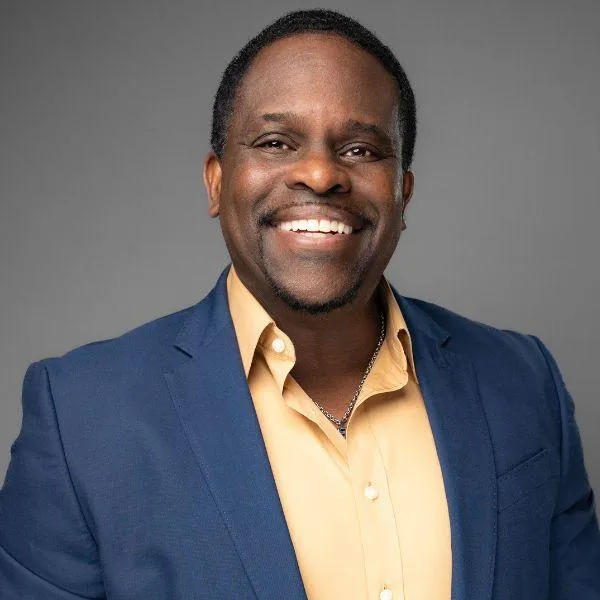 Professional headshot of a smiling Black male officer in business professional attire, taken for a social profile