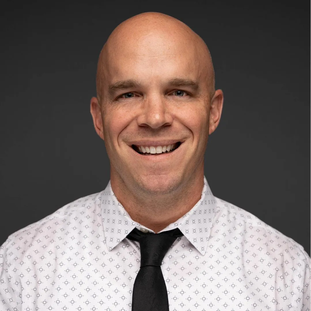 Professional headshot of a White male officer in business attire, smiling