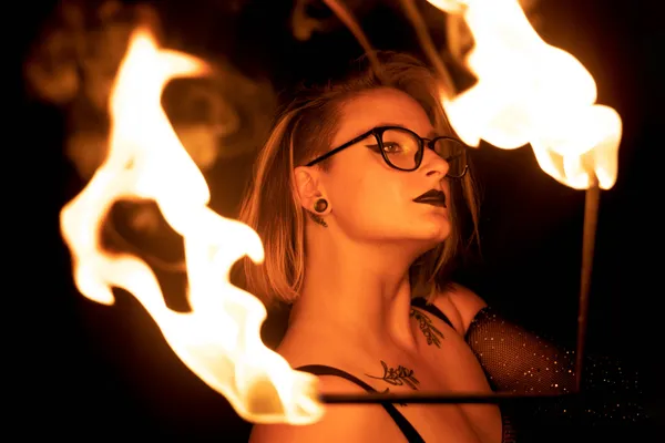 A woman wearing glasses poses behind fire