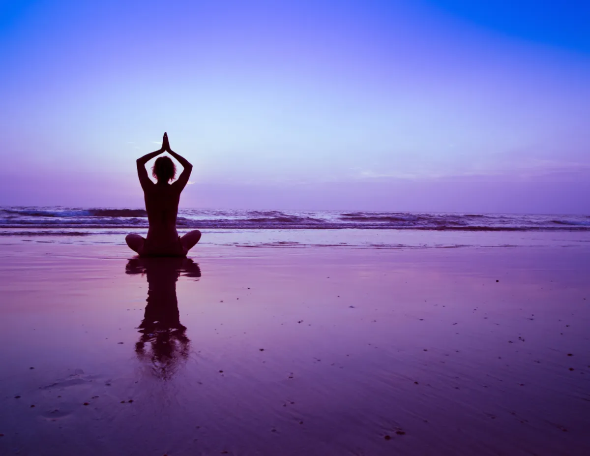 person meditating on beach