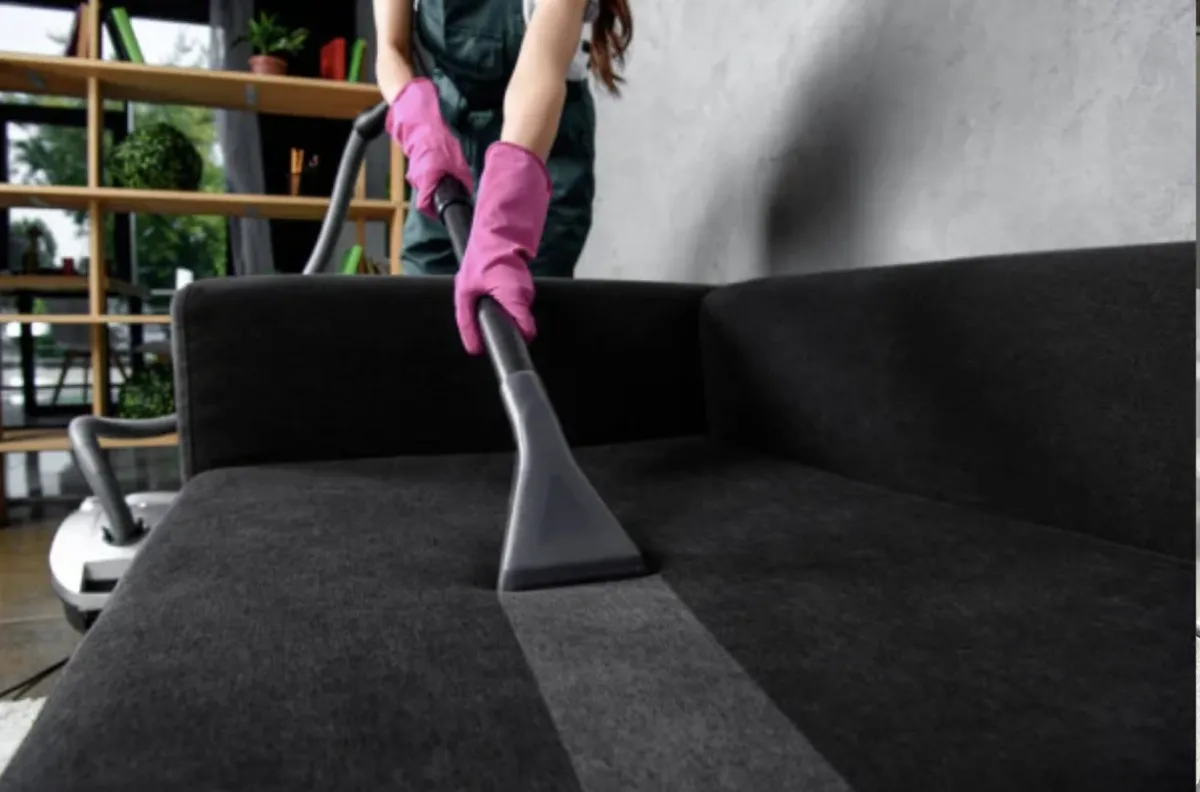 a woman cleaning upholstery and wearing pink gloves