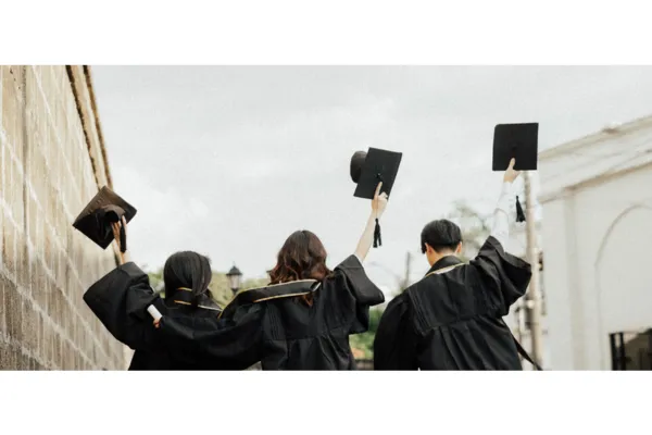 A group of university graduates are raising their graduation caps.