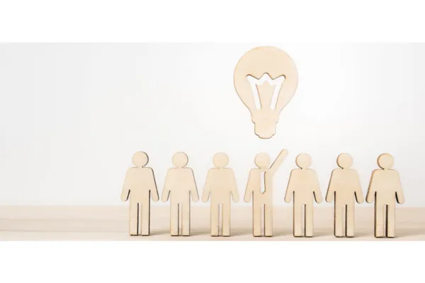 There are six people standing in front of a lightbulb.