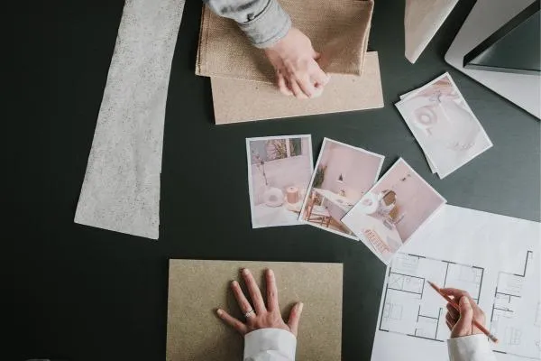 Overhead view of a designer's workspace with material samples, inspirational images, and floor plans, illustrating the planning stage of home remodeling.