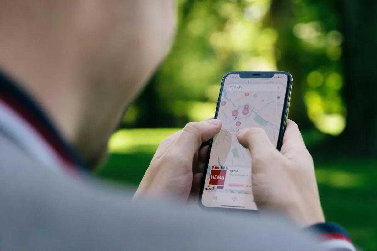 Person using a smartphone to navigate a map application outdoors