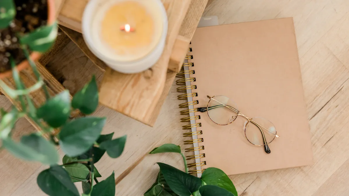 blog image with a candle, notepad, glasses and greenery