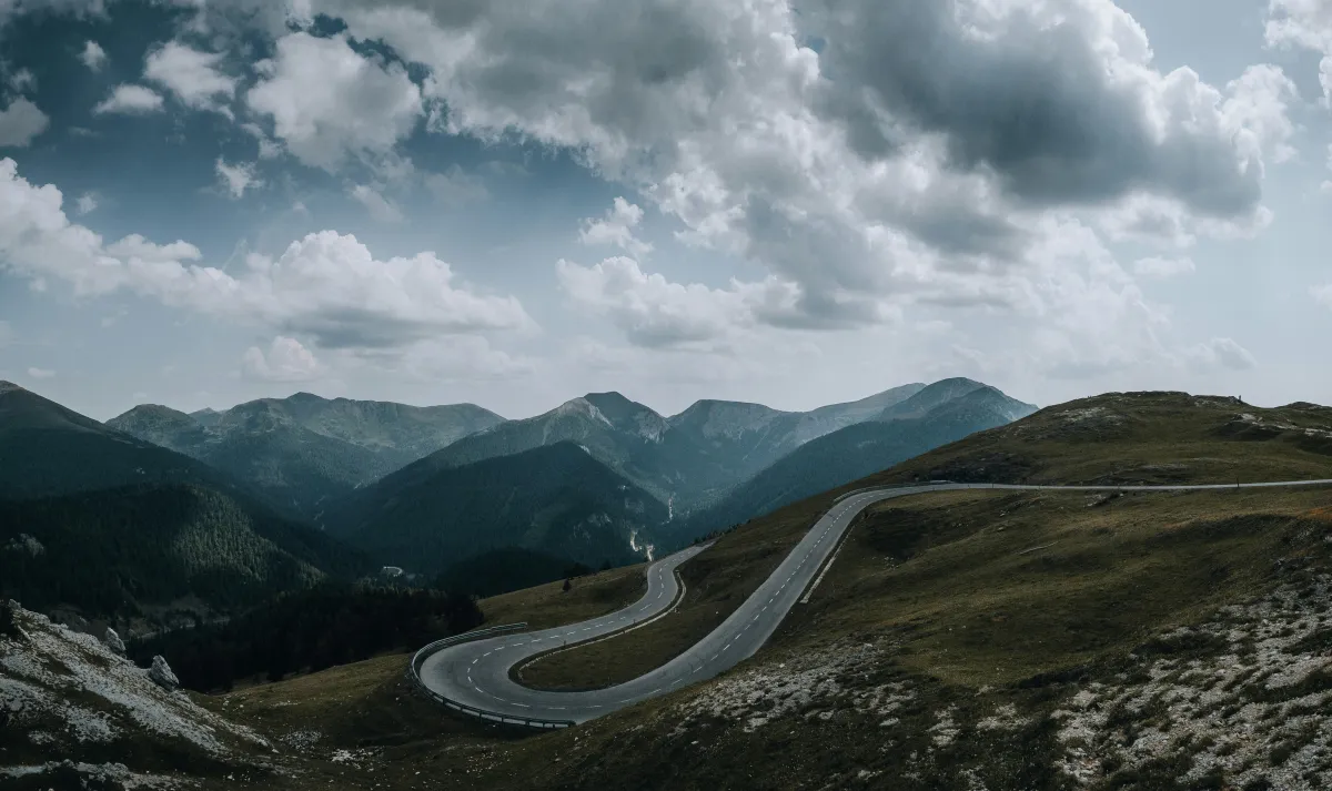 Curving road through a peaceful valley, representing the non-linear path of emotional healing and self-compassion.