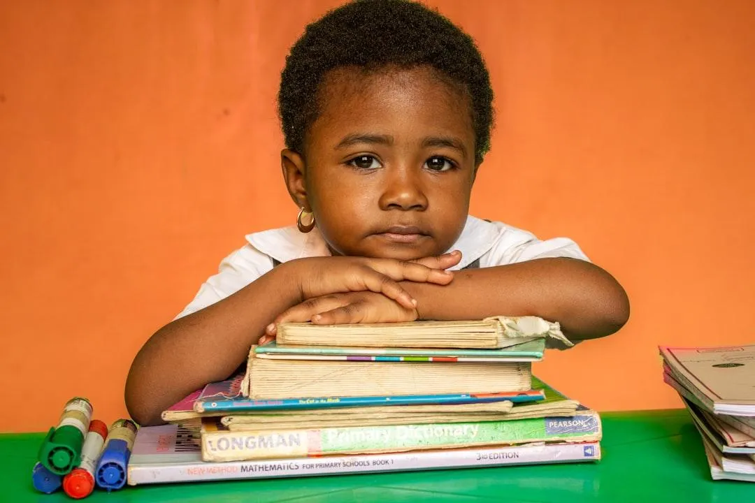 African American Boy with his arms crossed and chin on some books