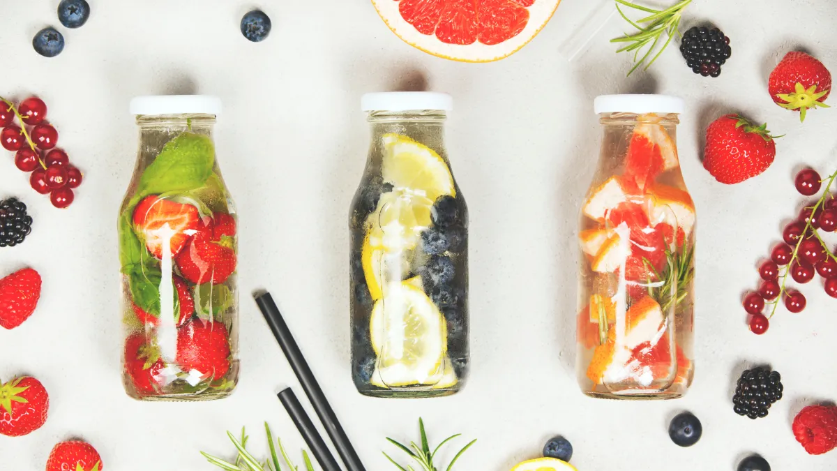 Three bottles filled with colorful fruit and vegetables, showcasing a variety of healthy produce.