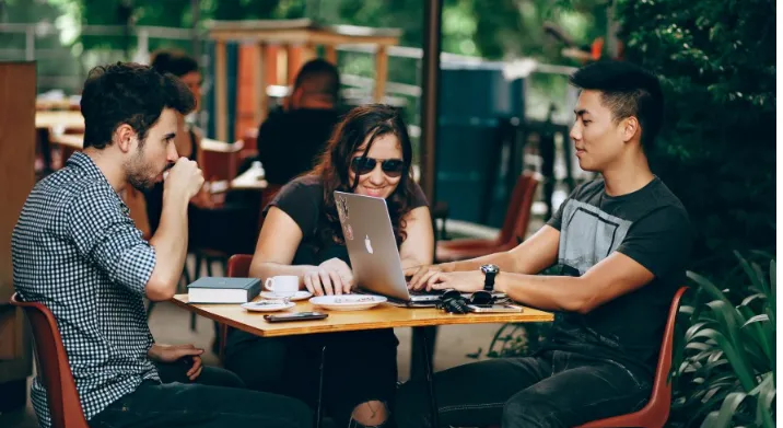  A group of young professionals sitting in a cafe around a laptop