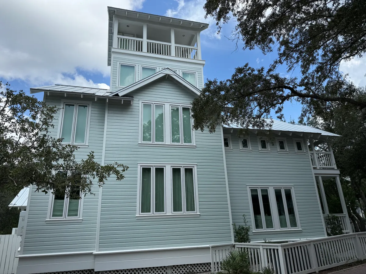 Large light blue coastal home with clean siding and windows after soft wash house washing service.