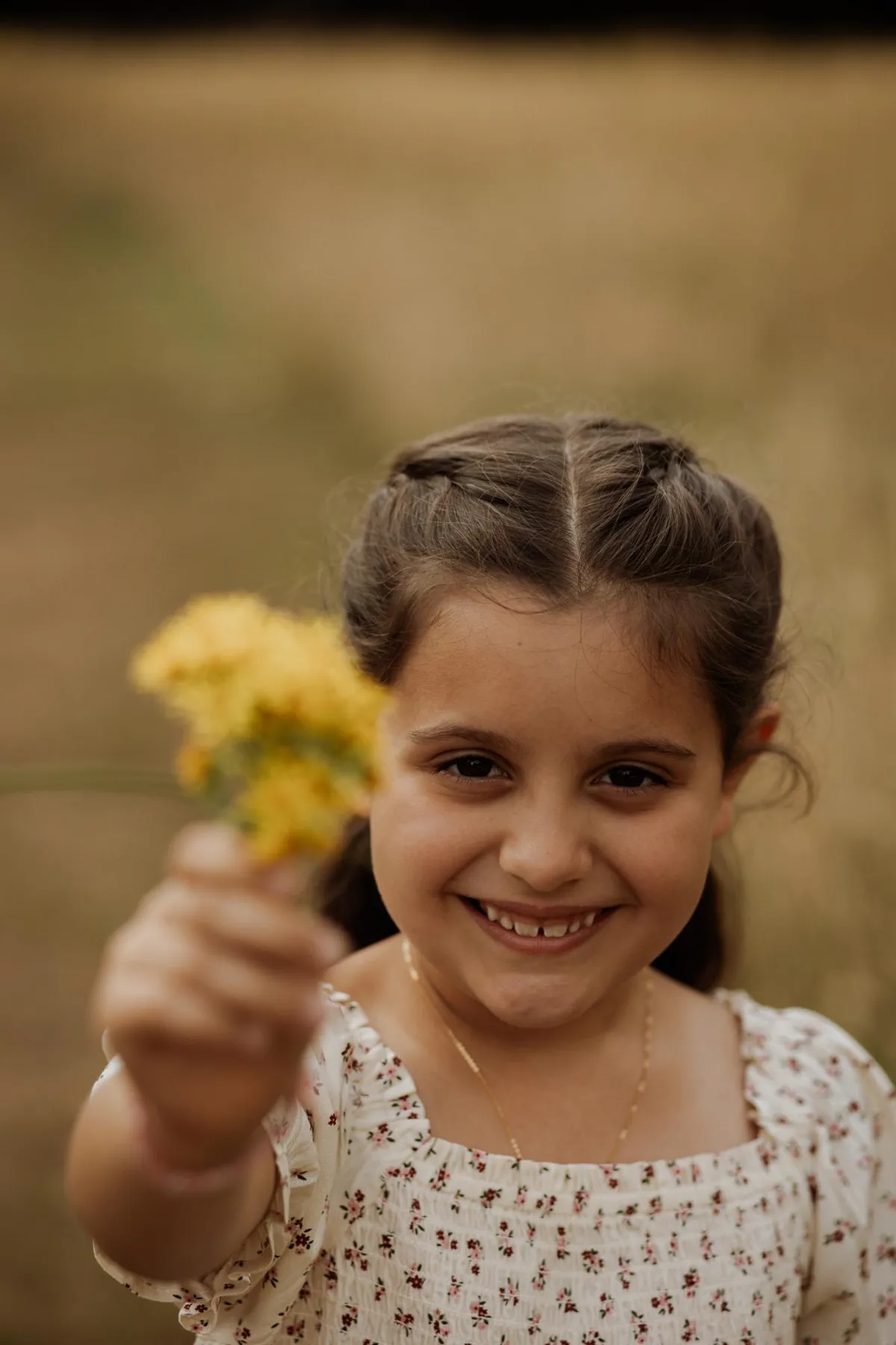 Photo of little girl holding a yellow flower to the camera in suffolk