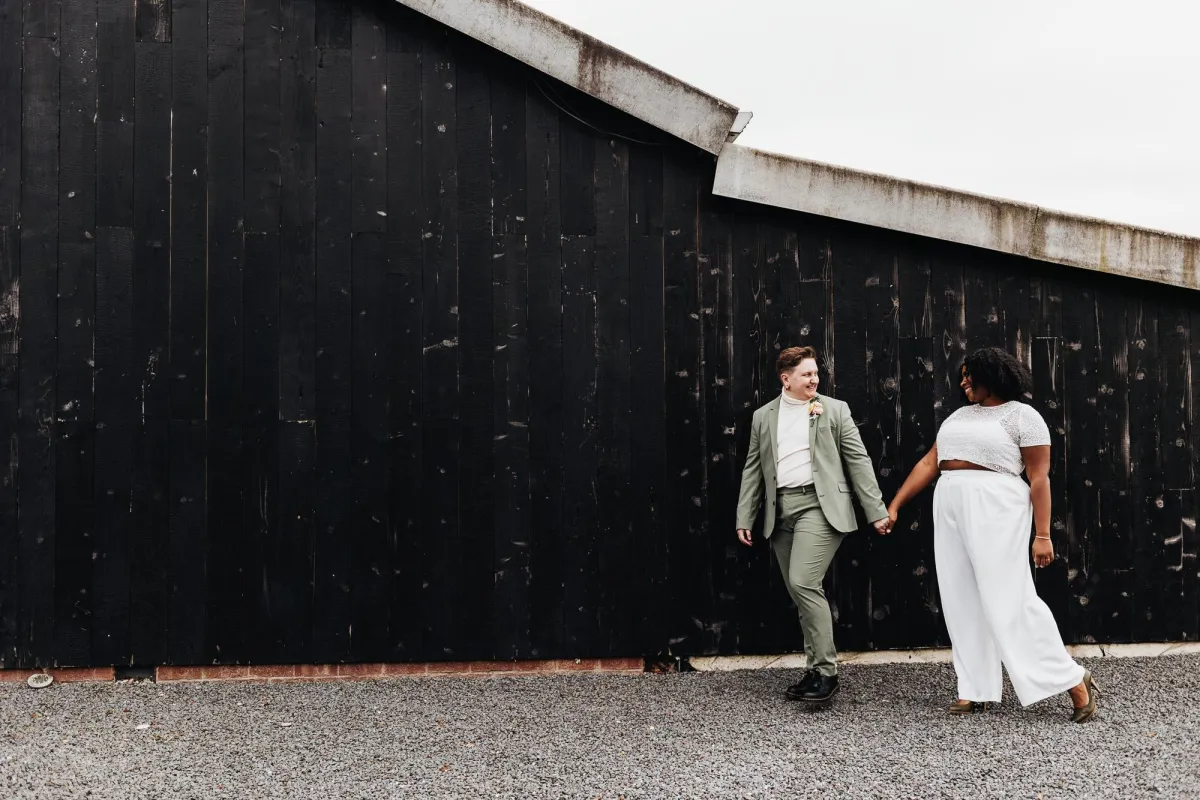 Photo of a non-binary wedding couple walking together and looking at each other taken by LGBTQ+ friendly Photographer