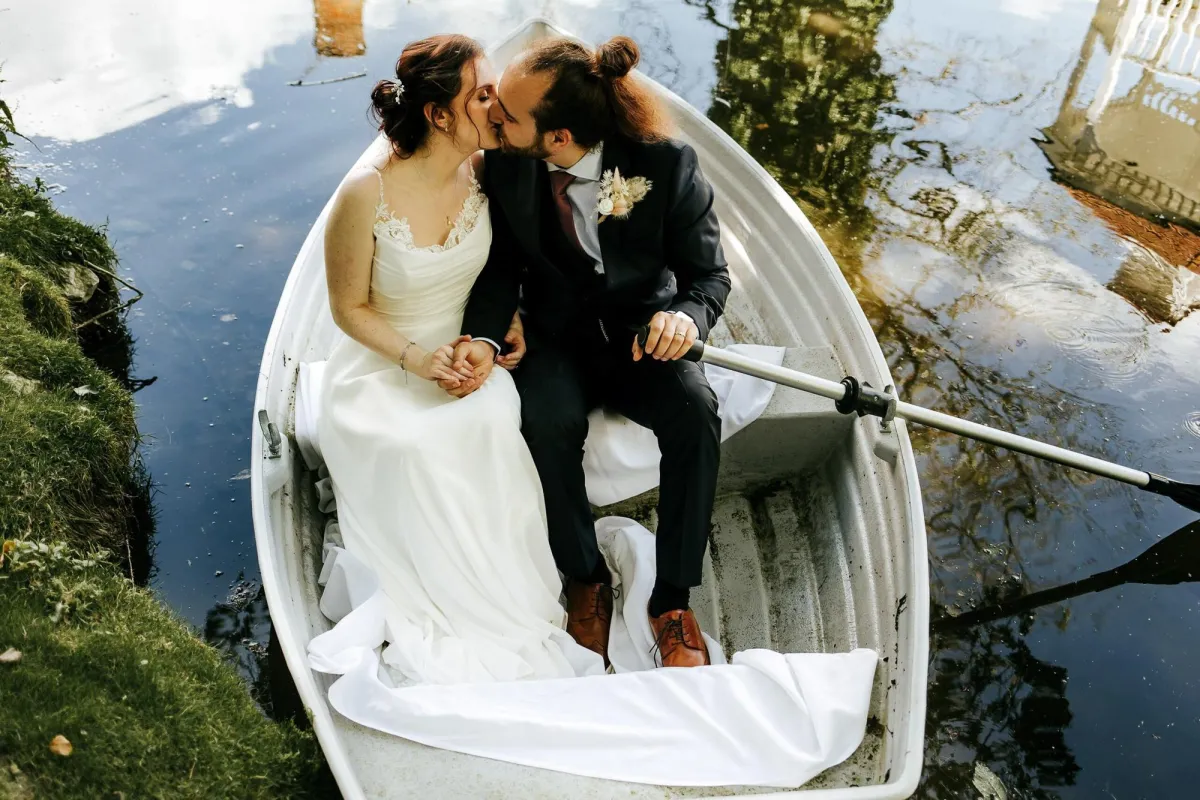 Photo of wedding couple sitting in a boat and kissing at Sheene Mill Wedding Venue