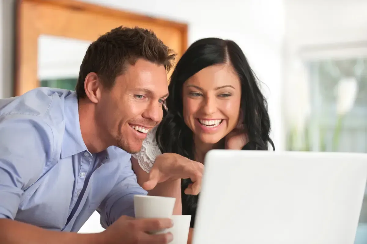 Smiling couple reviewing tax relief options online, feeling confident after learning how to remove IRS penalties.