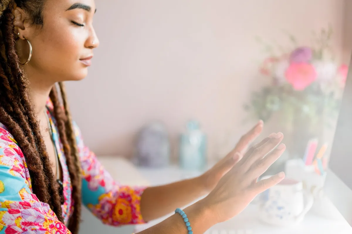 A woman practicing energy healing with her hands extended, eyes closed, in a serene setting.