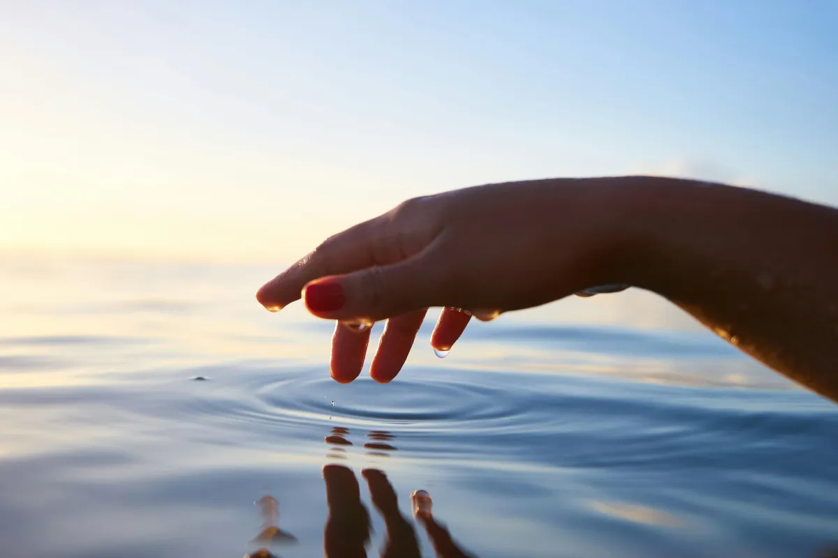 Hand reaching out over the water